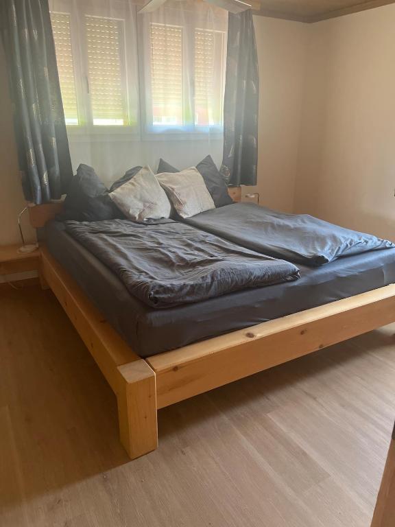 a large bed with a wooden frame in a bedroom at Landliebi 3-room apartment in Faulensee