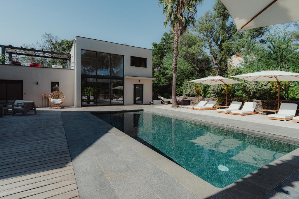 a swimming pool with chairs and umbrellas next to a house at Villa Ryx avec piscine in Grimaud