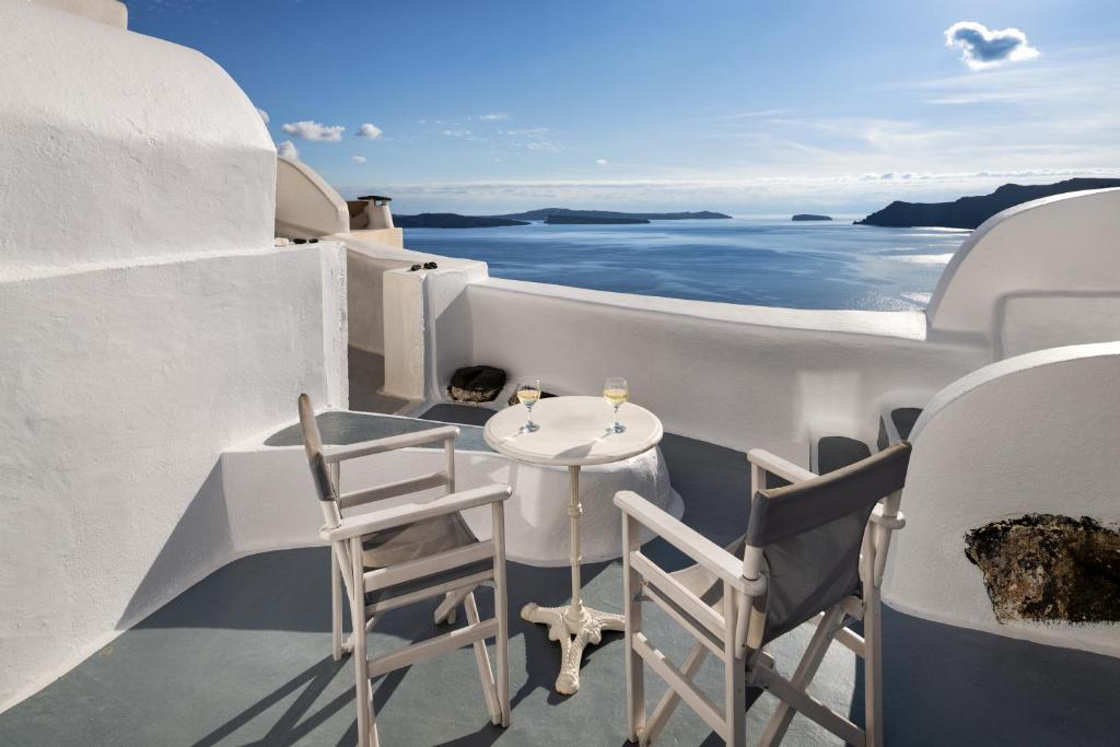 a table and chairs on a balcony overlooking the ocean at ROCK CAVE HOUSE in Oia