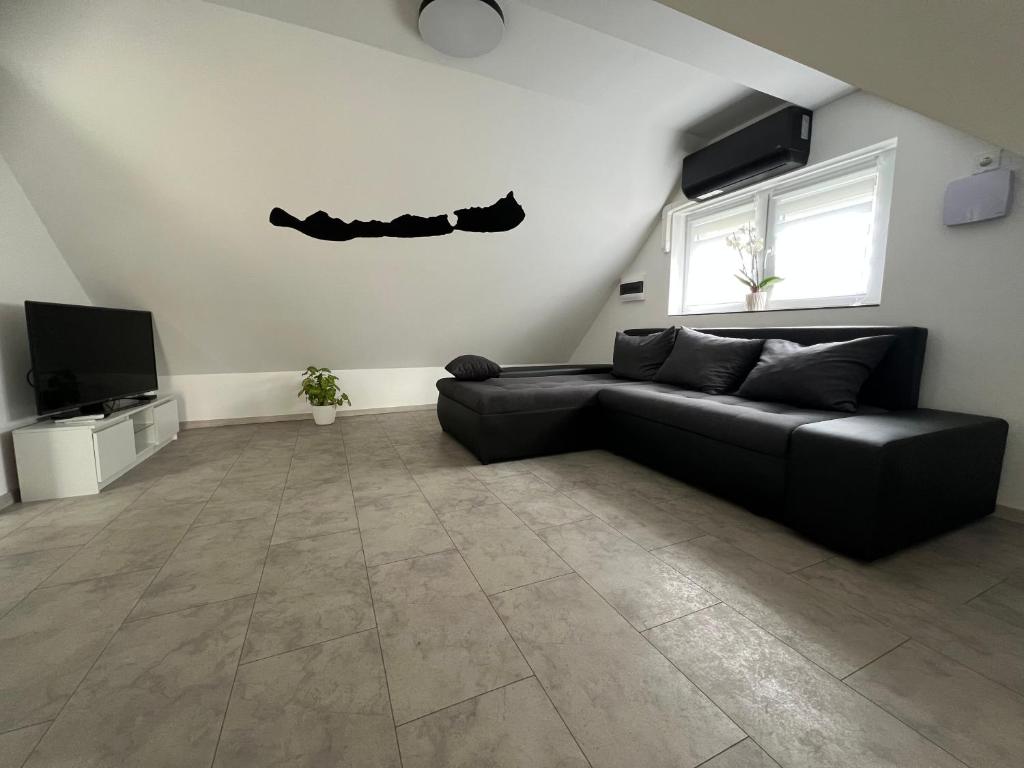 a living room with a black couch and a tv at Garda Apartman in Balatonfenyves
