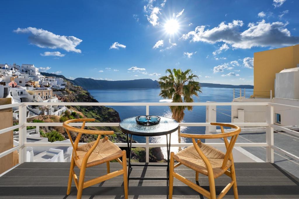 a balcony with a table and chairs and a view of the ocean at VITAMIN STUDIO in Oia