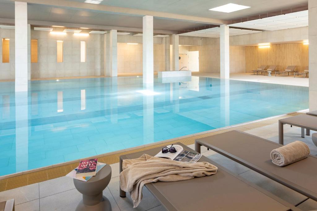a large blue swimming pool with a table in front of it at Parkest Hôtel & Spa in Genas