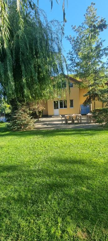 a building with two picnic tables in a field of grass at Pension Puiu in Dunavăţu de Jos
