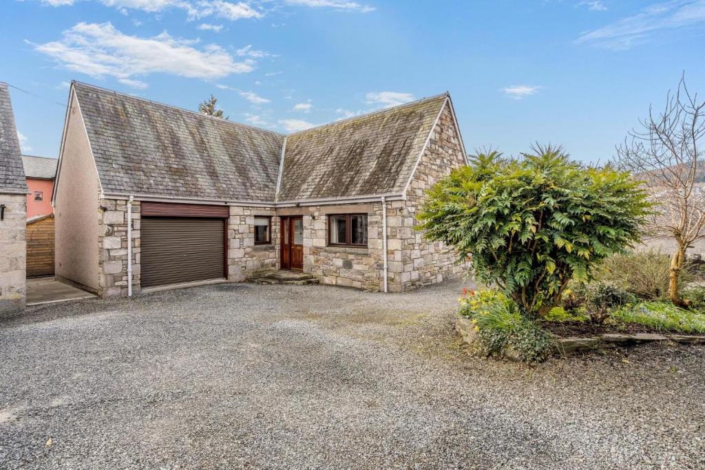 a stone house with a garage and a tree at 3 Bed in Pitlochry oc-t37864 in Pitlochry