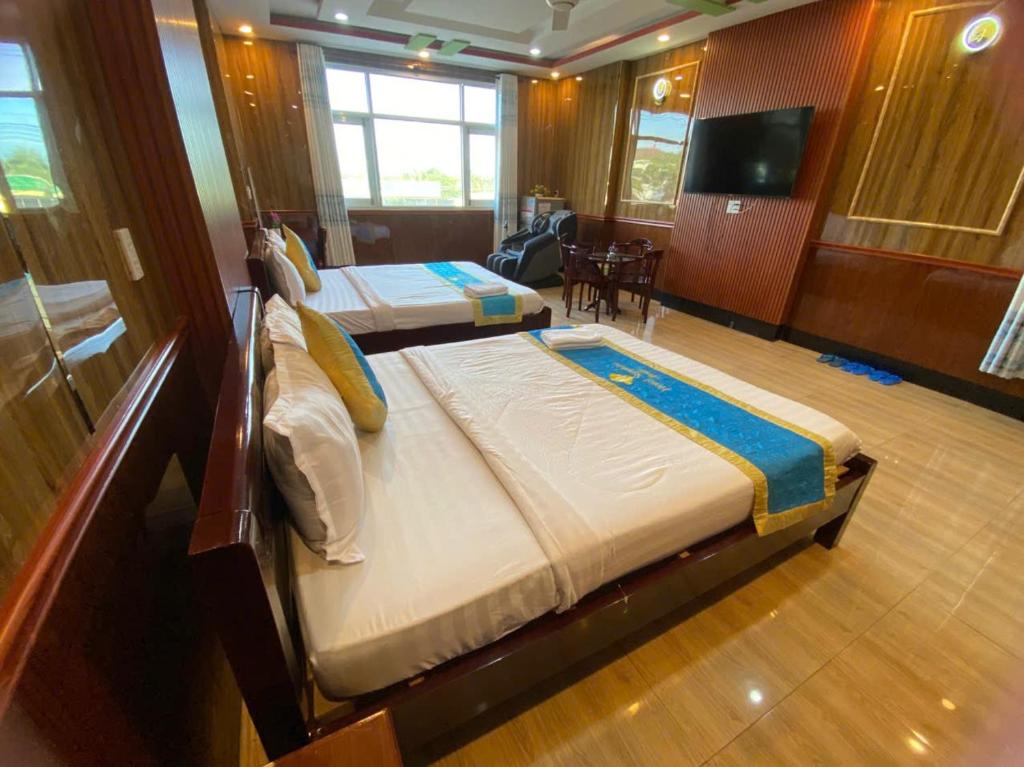 a bedroom with two beds and a tv in it at Khách Sạn Sapphire in Gò Công