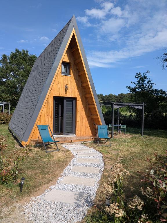 a triangular house with two blue chairs and a path at Tipi Big Foot in Vivy