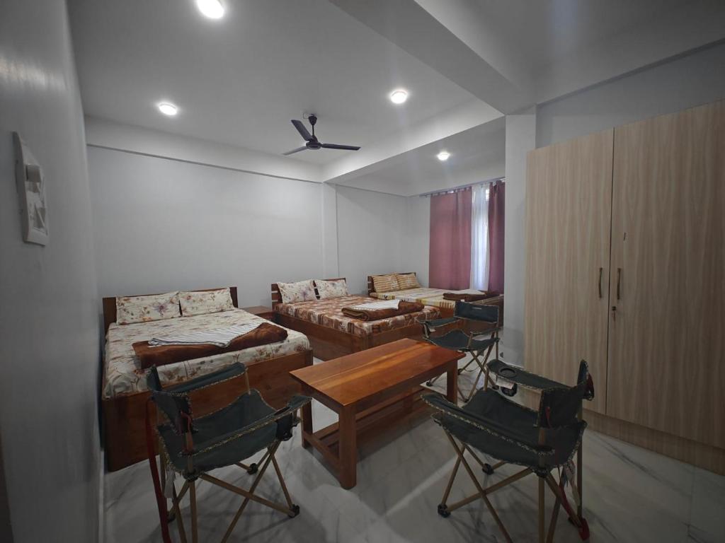 a room with four beds and a table and chairs at Yang home stay in Dirang Dzong