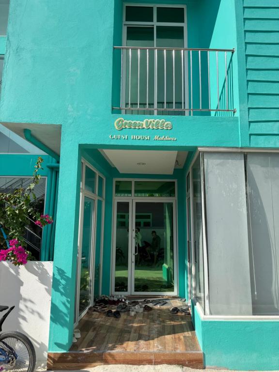 a blue building with a balcony and a door at Green Villa in Huraa