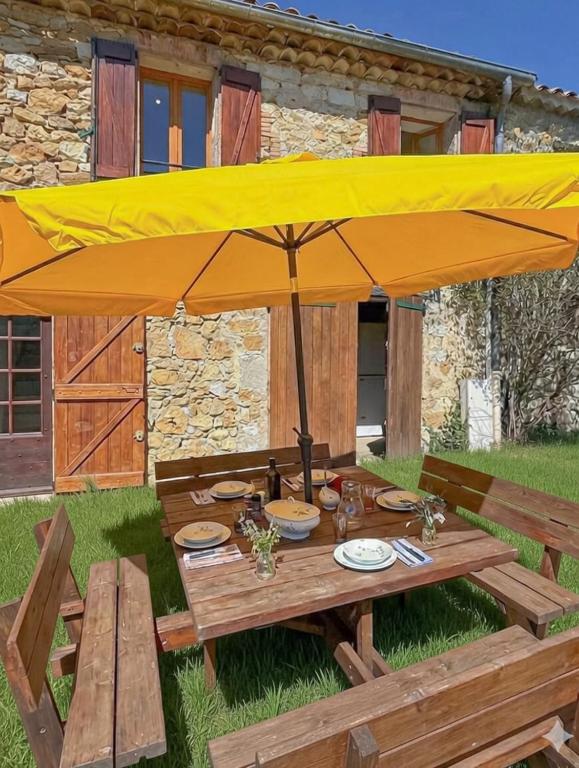 a picnic table with a large yellow umbrella at Maison de campagne T3 Nature in La Martre