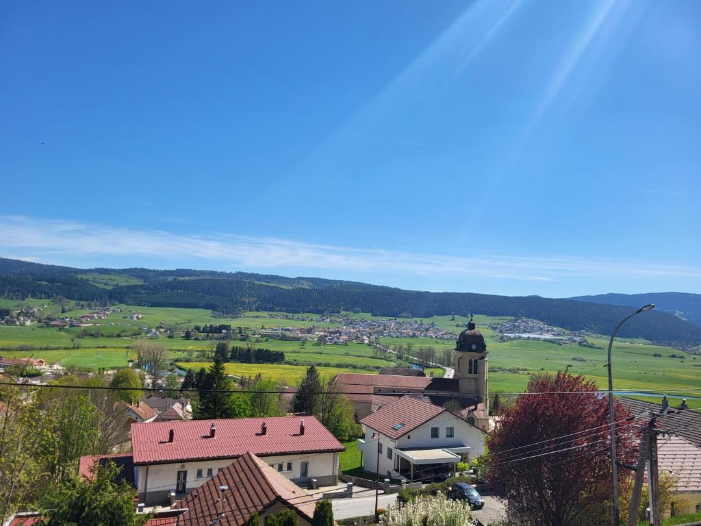 a small town with a church and a field at Logis des Bouchons in Morteau