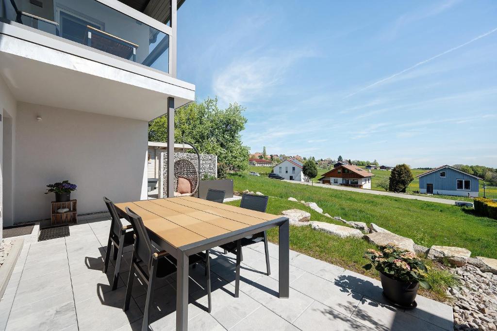 a wooden table and chairs on a patio with a yard at Chalet Seewald - Apartment in Seewald