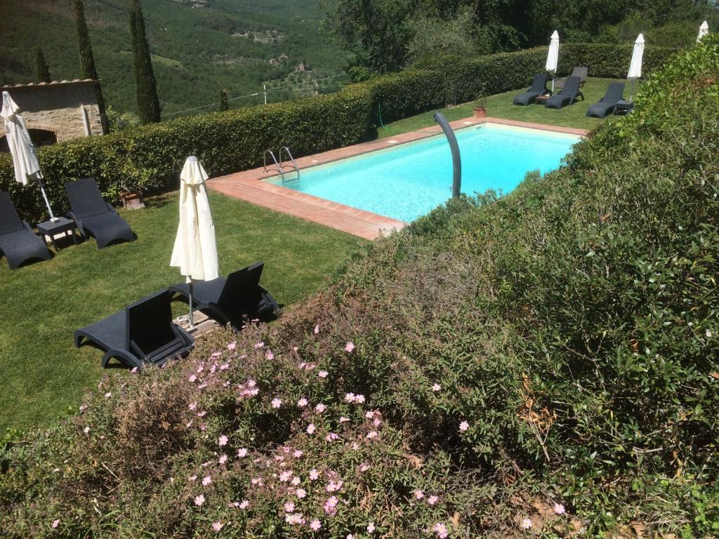 a swimming pool in a yard with chairs and an umbrella at Residenzia Del Sogno in Castellina in Chianti