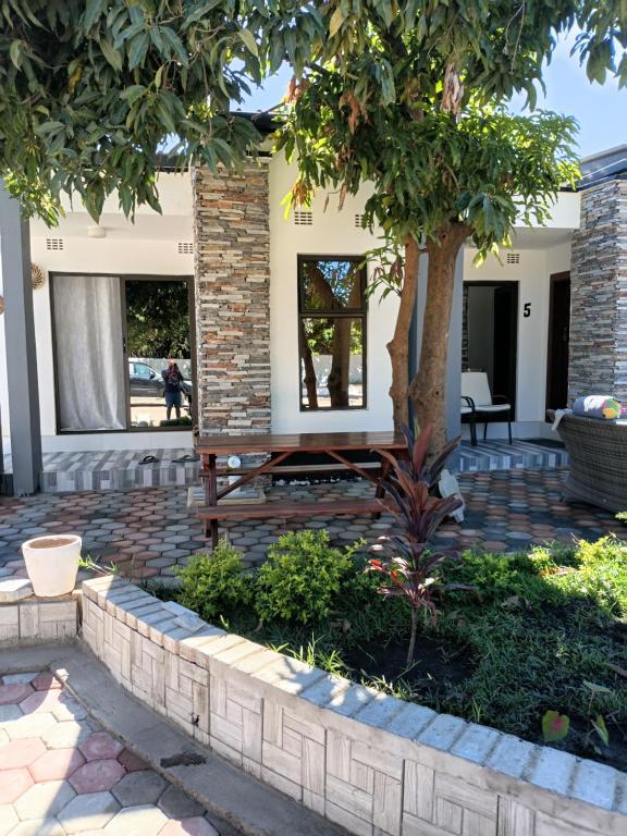 a patio with a bench under a tree at Tiptree Lodge in Livingstone