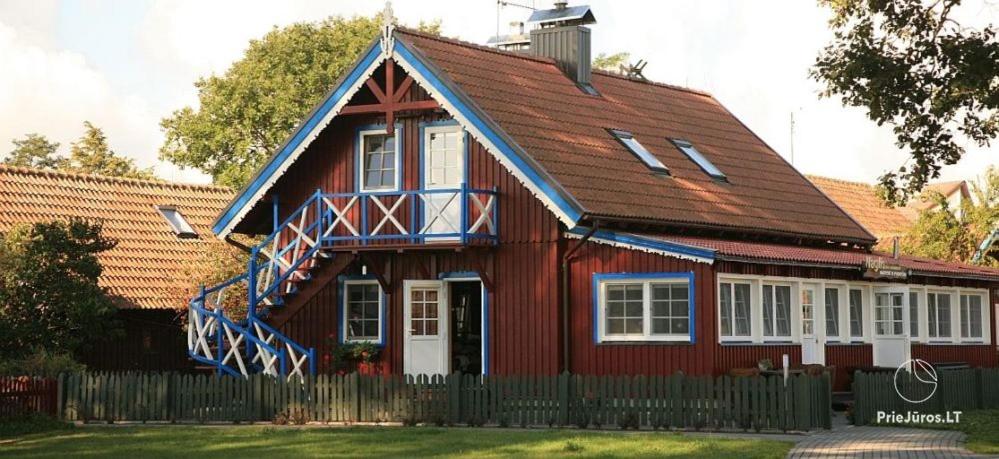 a red house with a gambrel roof at Guest House Naglis in Neringa