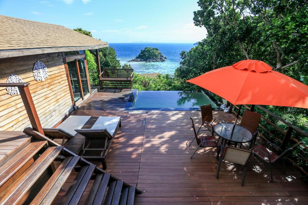 a deck with a table and an umbrella at Serendipity Beach Resort Koh Lipe in Ko Lipe