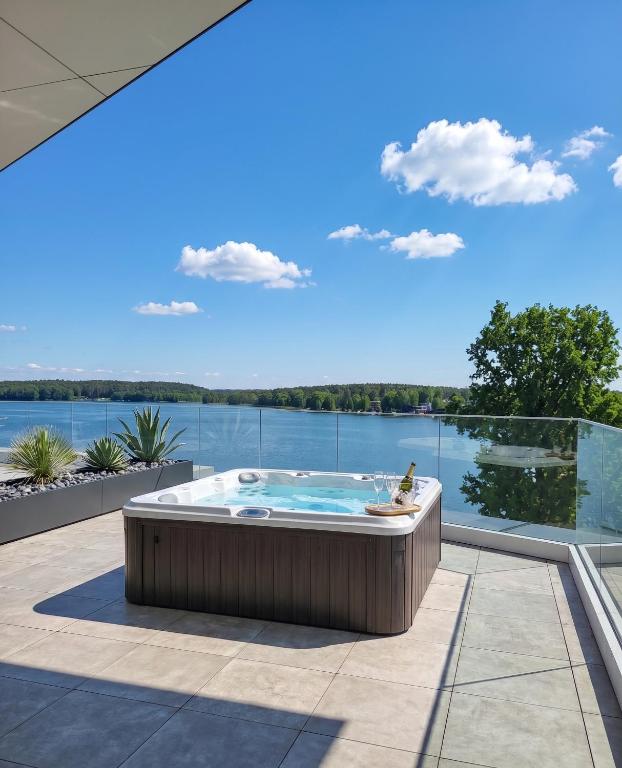 a hot tub on a patio with a view of the water at Apartament Premium nad jeziorem, przy samej plaży miejskiej in Olsztyn