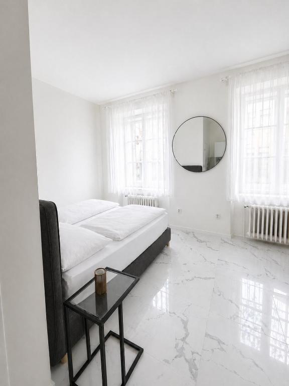 a white bedroom with a bed and a mirror at Jela`s Suite in Vienna