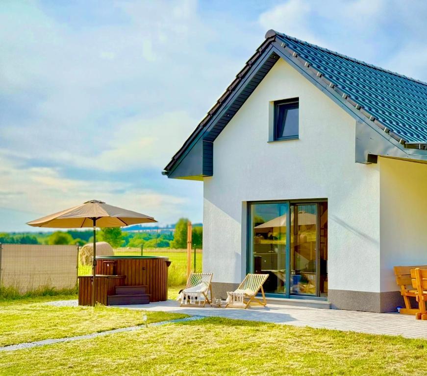 a house with a patio and an umbrella at Pod Izerskim Niebem - kameralny domek z balią, w sąsiedztwie Świeradowa-Zdroju in Mroczkowice