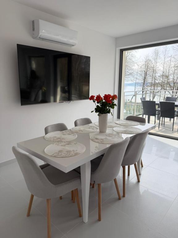 a white dining room table with chairs and a vase of flowers at MazuryLive in Węgorzewo