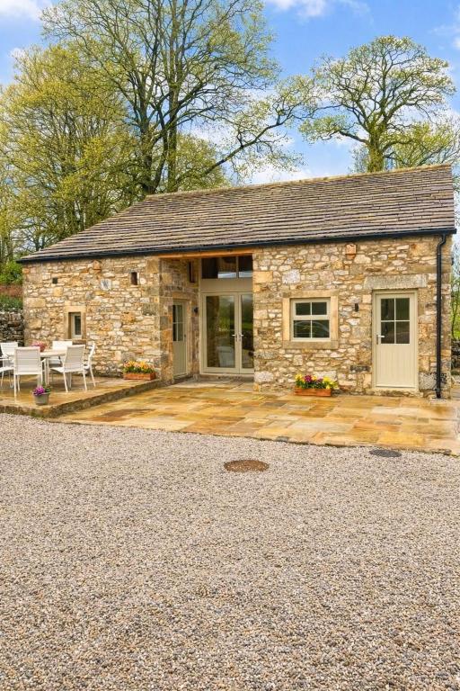 a stone cottage with a patio in front of it at Ladywell Barn in Threshfield