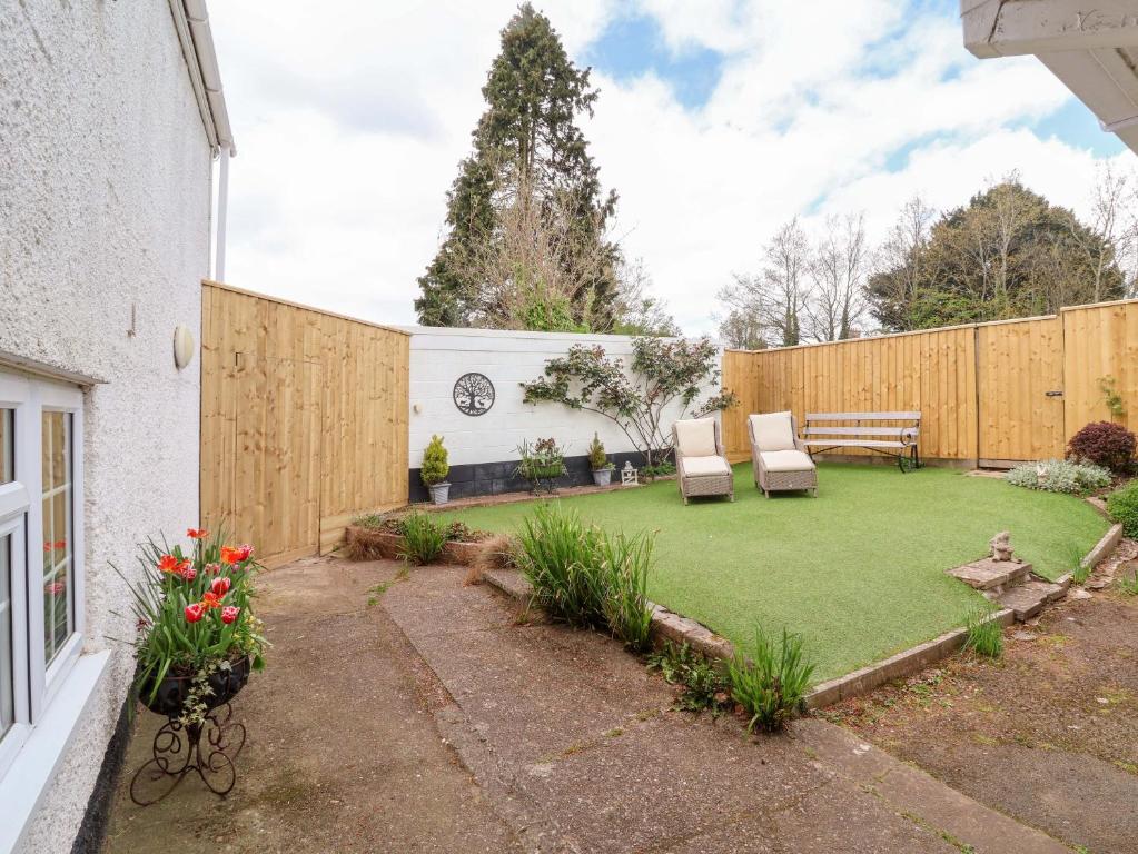 a backyard with a lawn with two chairs and a bench at The Apple Loft in Exeter