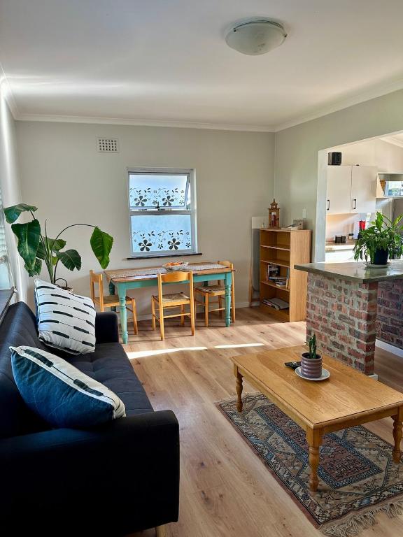 a living room with a couch and a table at Spacious cottage with a private garden in Somerset West