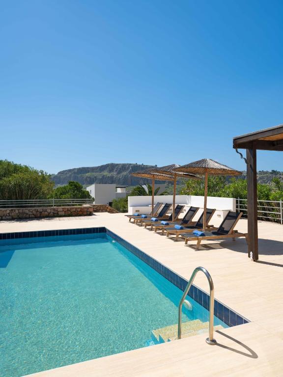 a swimming pool with chaise lounge chairs and a swimming poolvisor at Aethrion Villa Lindos in Lindos