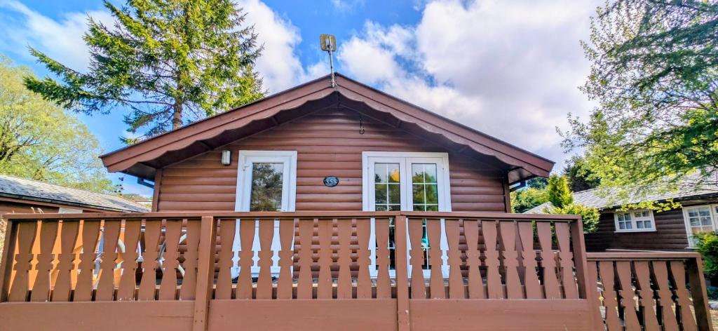 a log cabin with a wooden fence at Cabin Gezellig in Trawsfynydd