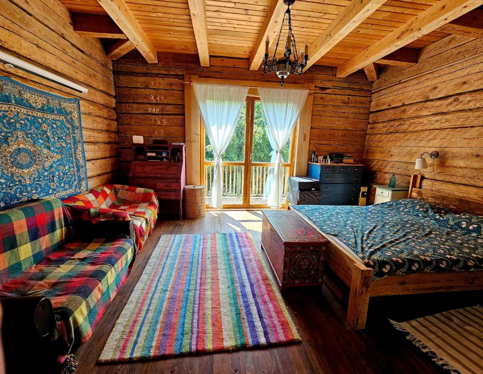 a living room with a couch and a bed in a log cabin at Gałęziówka, Doły Biskupie in Kunów