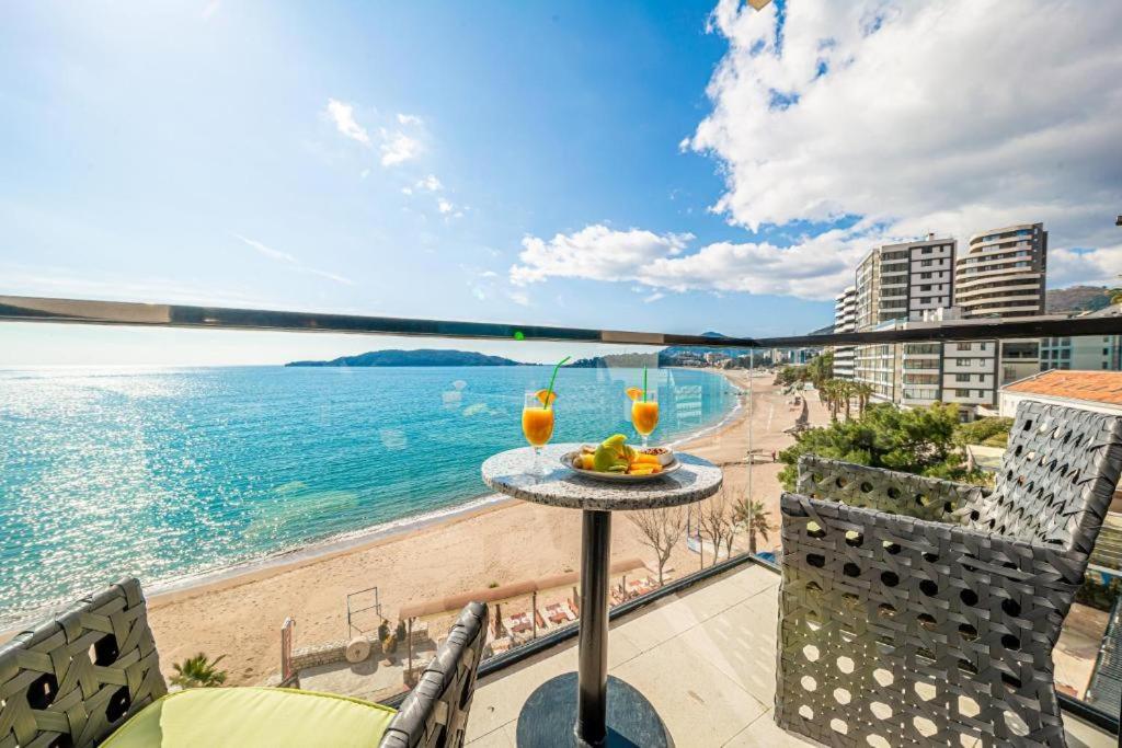 a view of the beach from a balcony with two drinks at Hotel Aleksandar Rafailovići in Budva