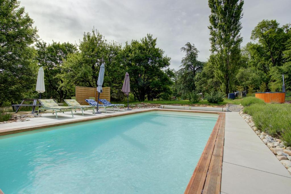 a swimming pool in a yard with chairs and umbrellas at Les totems de Grésigne in Penne