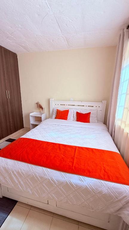 a bedroom with a large white bed with red sheets at Luxe homes 1b in Kabuku
