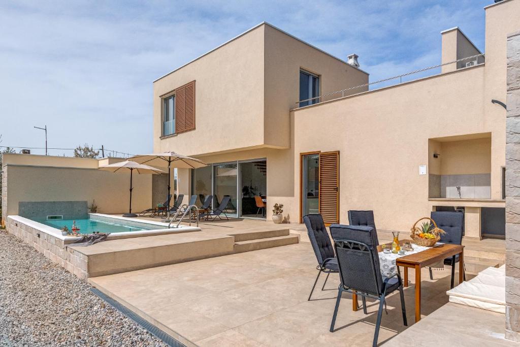 a house with a pool and a table and chairs at Villa Ventula in Šuljkove Kuće