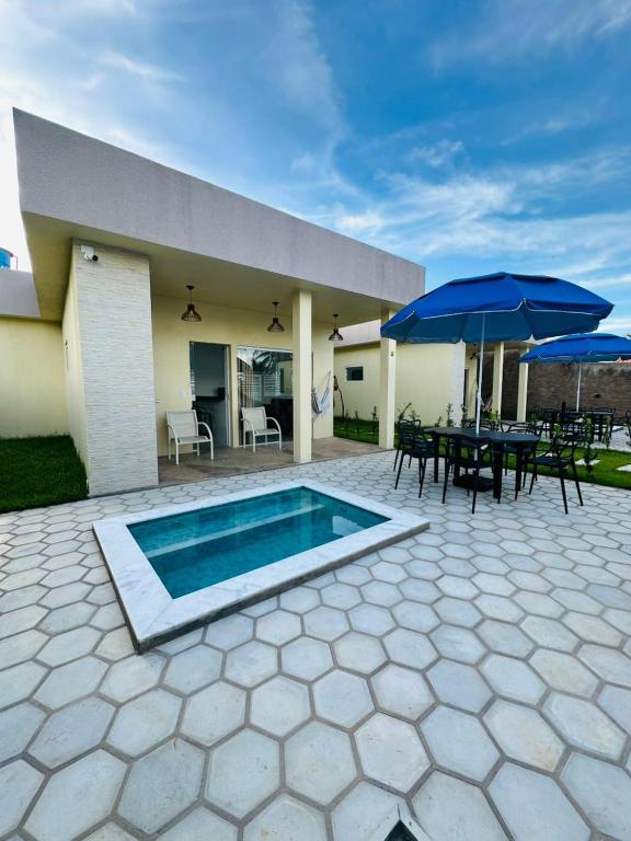 a house with a pool and a table and umbrella at Chalés do Mirante in Coruripe