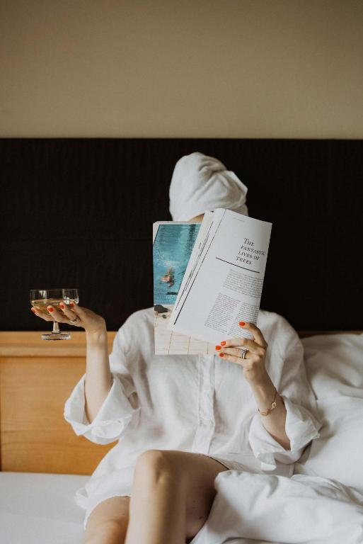 a woman laying in bed reading a book at SIEGI apartments & retreat - Merano Südtirol in Parcines