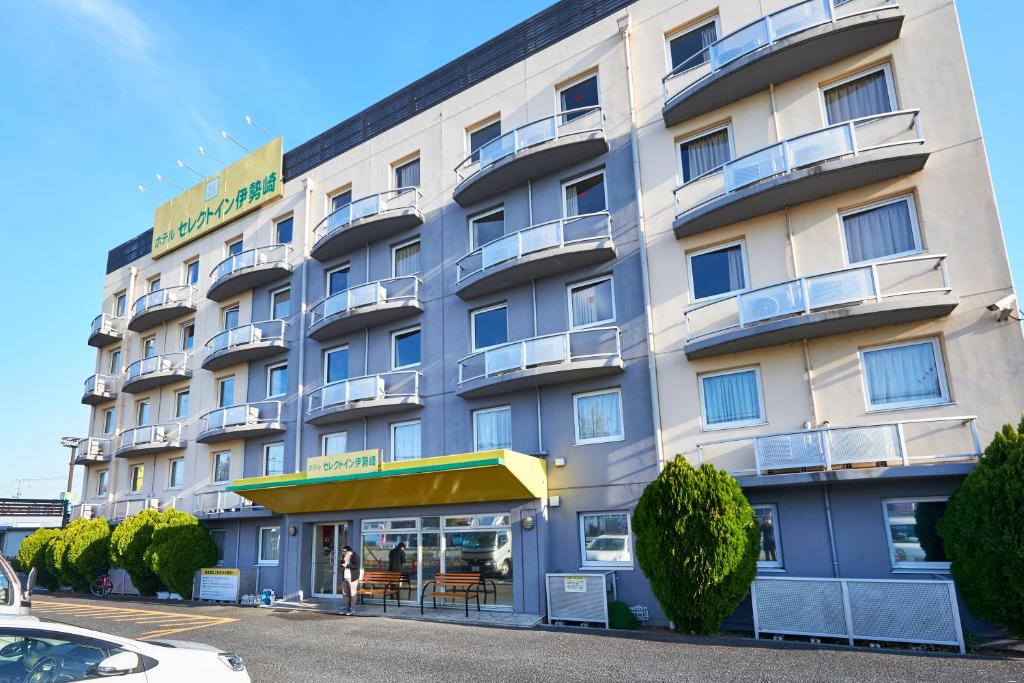Hotel Select Inn Isesaki في Isesaki: مبنى الفندق امامه طاولات وكراسي