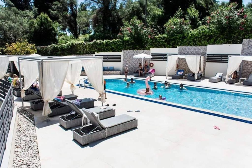 a swimming pool with lounge chairs and people in it at Fouxia Apartments and Studios in Perama