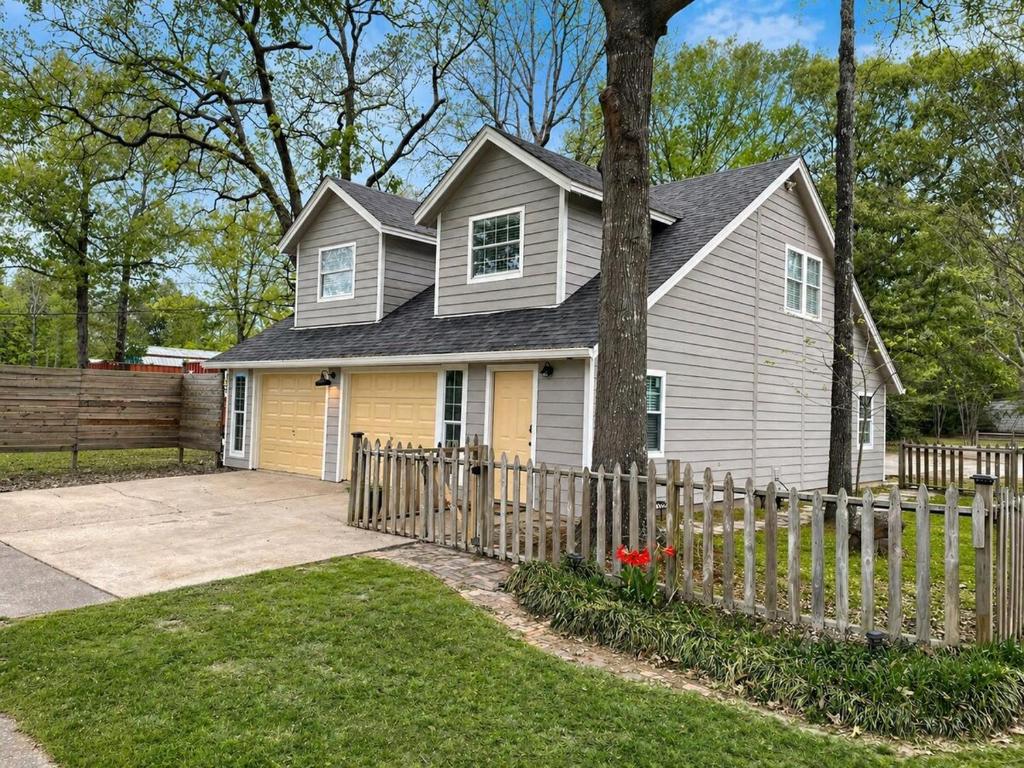 a house with a fence in front of it at Peach Door Cottage in Lufkin