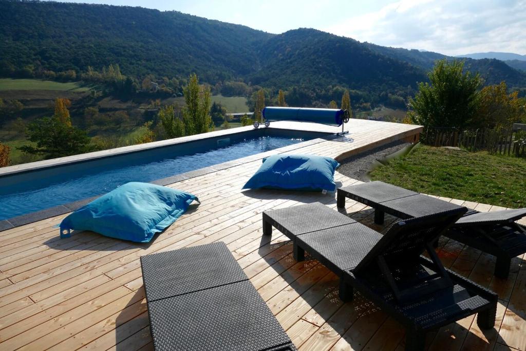 a swimming pool with blue pillows on a wooden deck at Villa d'architecte avec vue imprenable in Cobonne