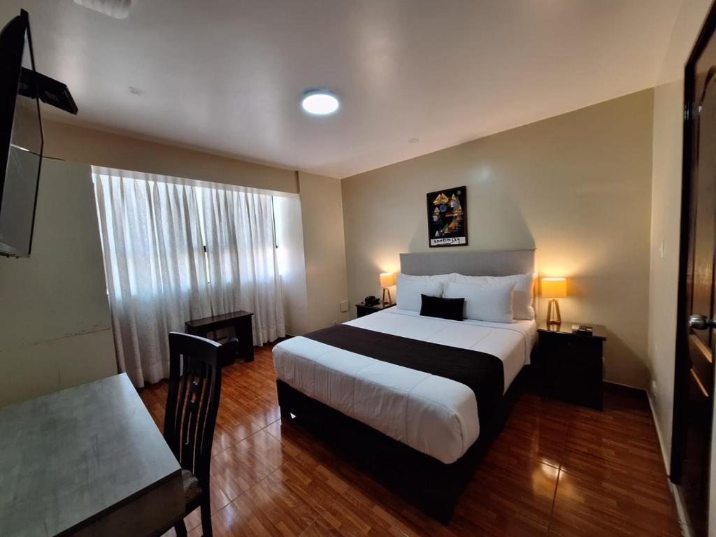 a hotel room with a large bed and a table at Epiqus Hotel in Lima