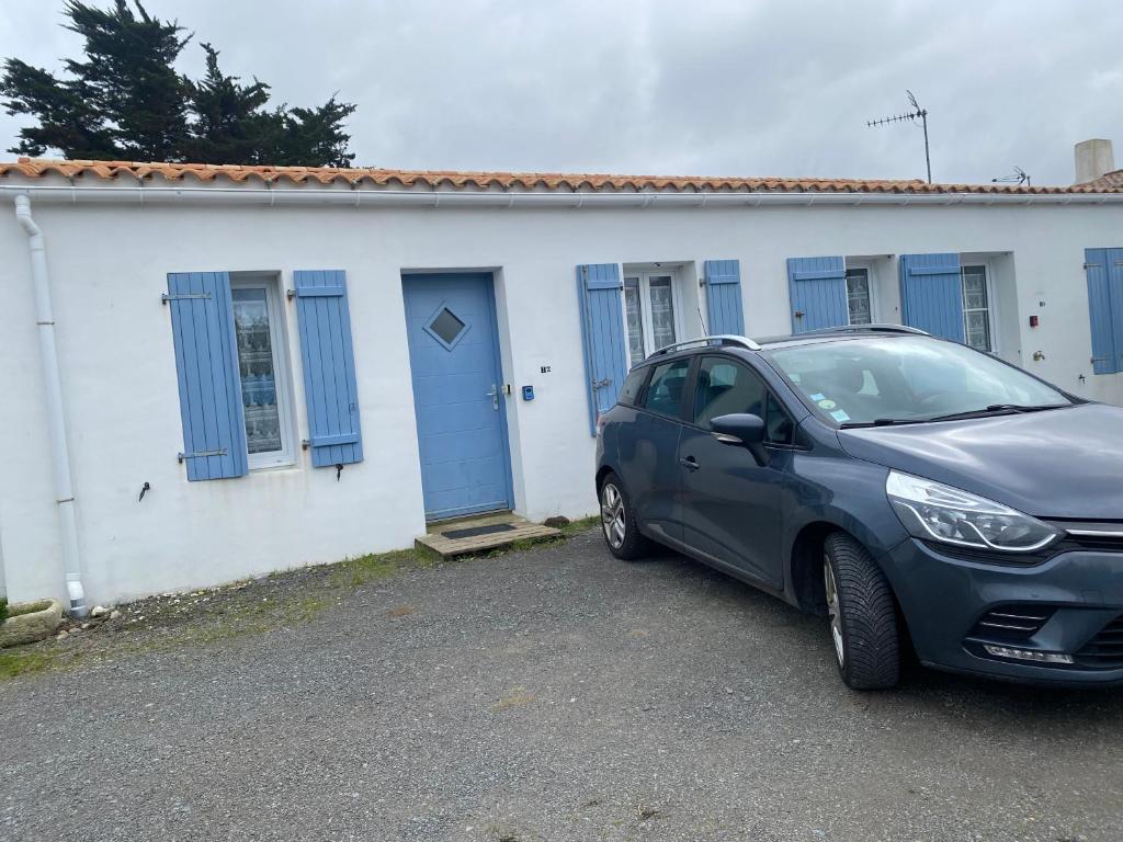 a car parked in front of a house with blue doors at hirondelle 1 in Noirmoutier-en-l'lle