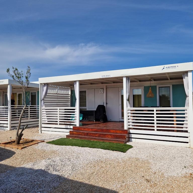 a white house with a porch and stairs on it at Mobile Homes Albatross in Pirovac