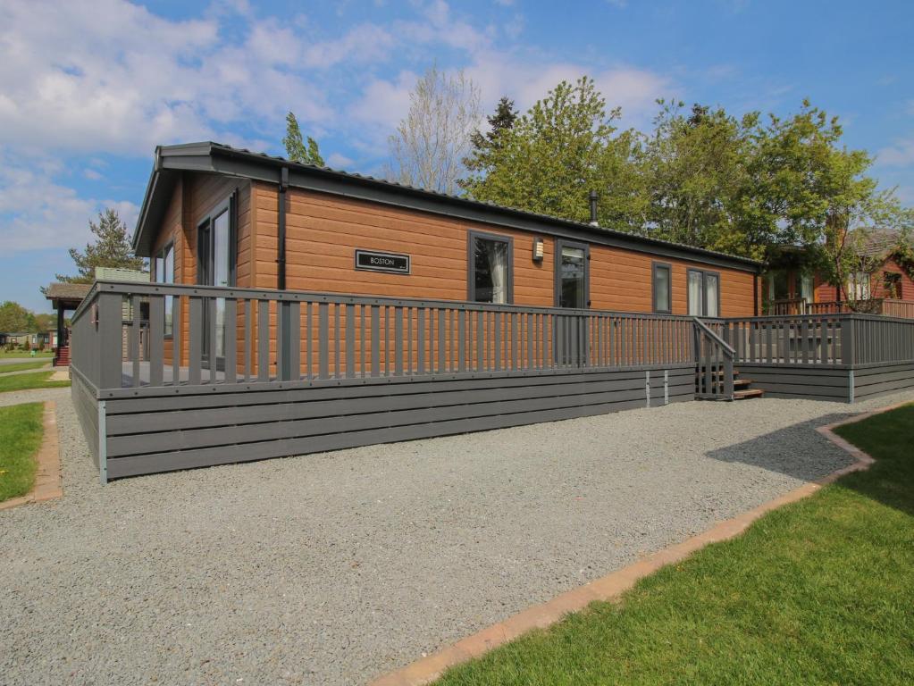 a small cabin with a large deck in a yard at Peony in Leominster