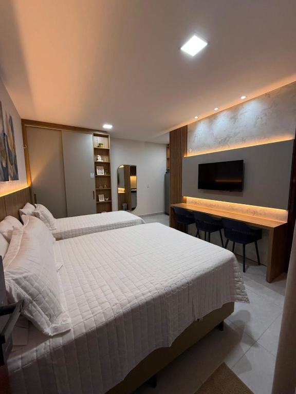 a bedroom with a bed and a desk and a television at Apartamento a 50m da praia em Camocim CE in Camocim
