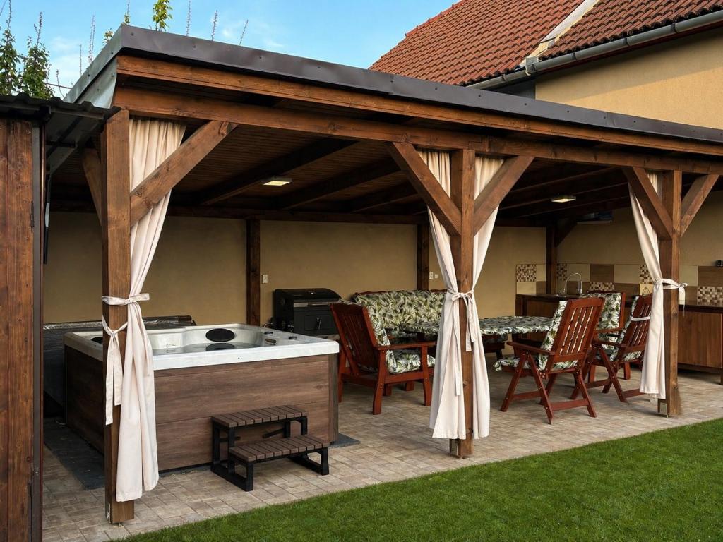 a wooden pavilion with chairs and a table on a patio at Barka Vendégház Tisza-tó in Abádszalók