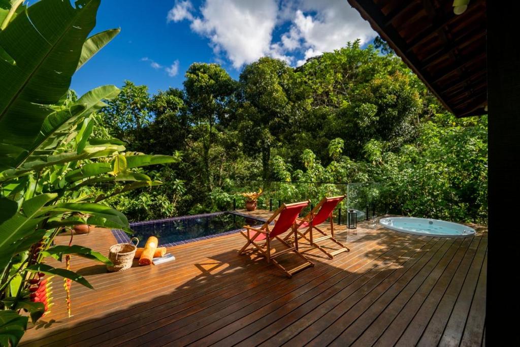 a deck with two chairs and a swimming pool at Cactus Chalés & Cabanas em lumiar in Lumiar