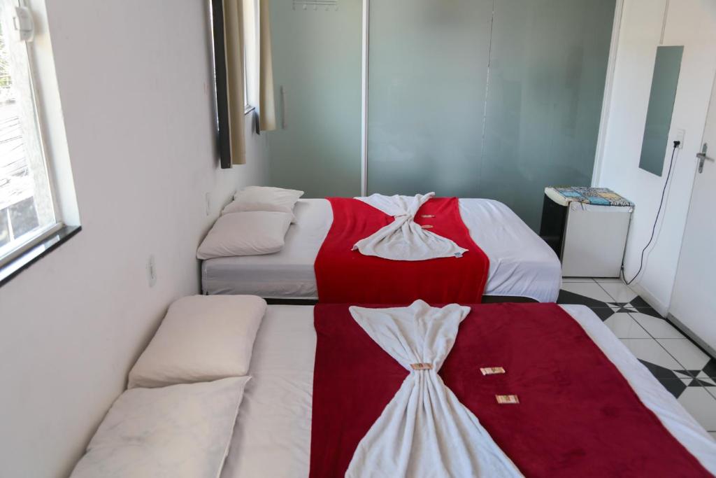 two beds with red and white sheets in a room at Donwtonw in Arraial do Cabo