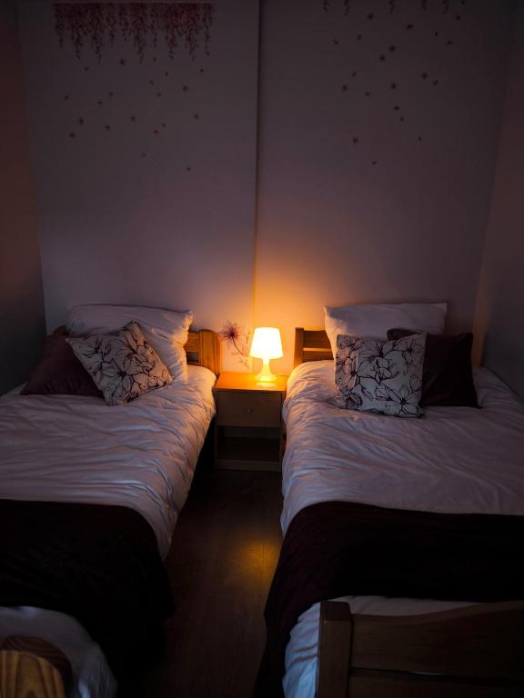 two beds in a room with a lamp on a table at Agroturystyka Kuźnia in Neple