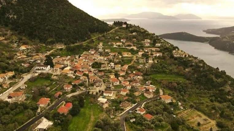 a small town on a hill next to a body of water at Julia's House in Mikros Gialos