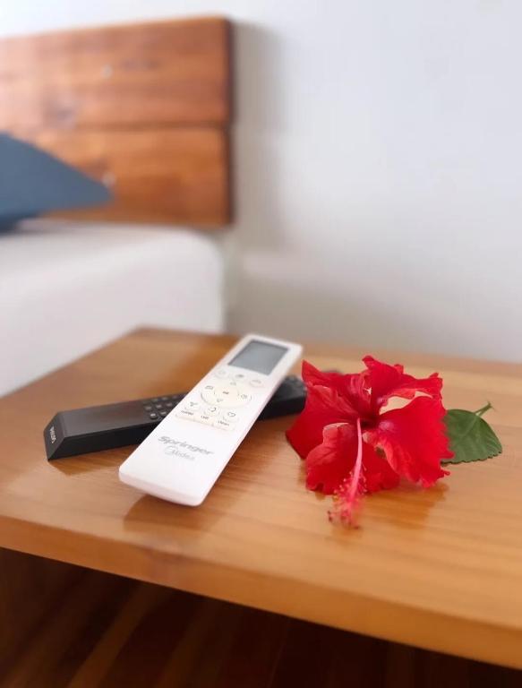 a remote control and a red rose on a table at Pousada do Nondas in Estivado